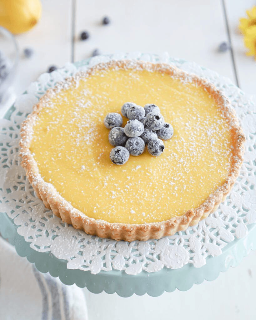 Lemon curd tart dusted with icing sugar and topped with blueberries